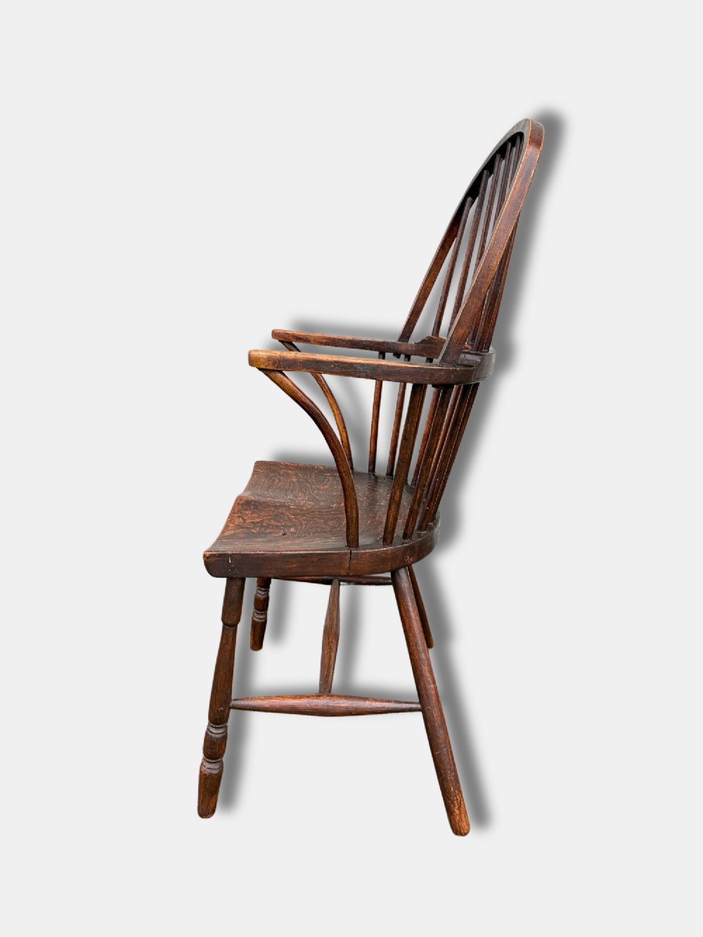 A dark timber hoop back Windsor armchair featuring vertical spindles, bentwood arm supports, a saddle seat, and turned legs with an H-stretcher. View V