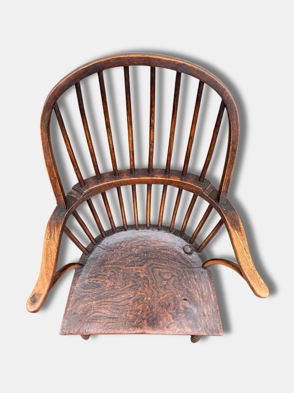 A dark timber hoop back Windsor armchair featuring vertical spindles, bentwood arm supports, a saddle seat, and turned legs with an H-stretcher. View VI