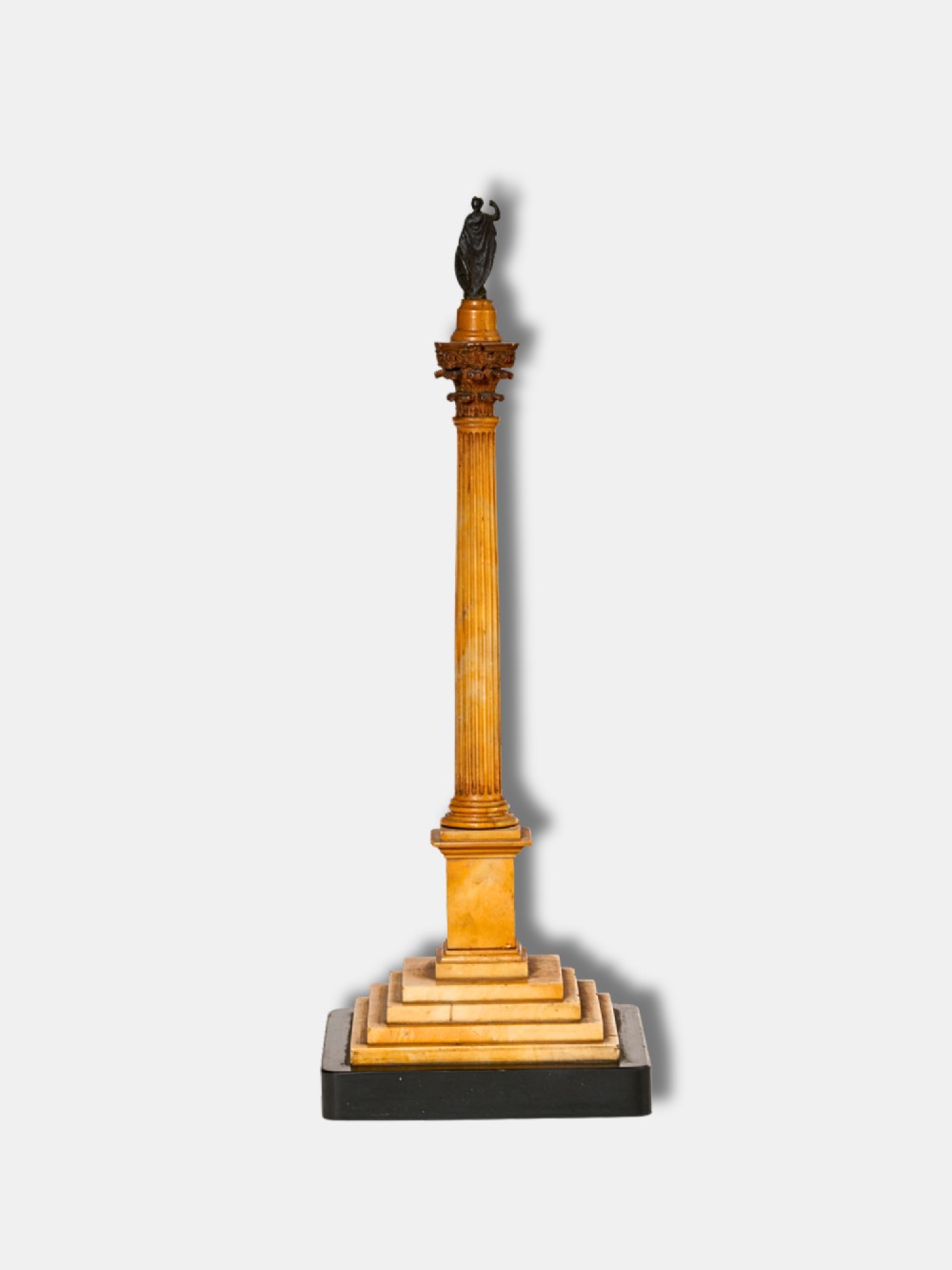A detailed miniature architectural model of the Column of Phocas carved from yellow Giallo Antico marble with a small bronze figure atop, set upon a stepped square base. View II