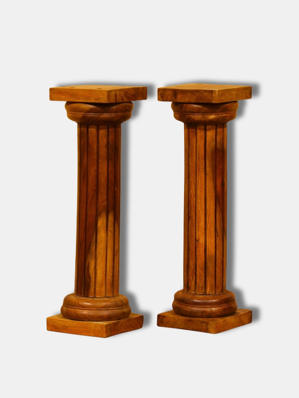 A pair of turned and fluted warm brown hardwood Neoclassical column pedestals with square base plinths and capital tops.