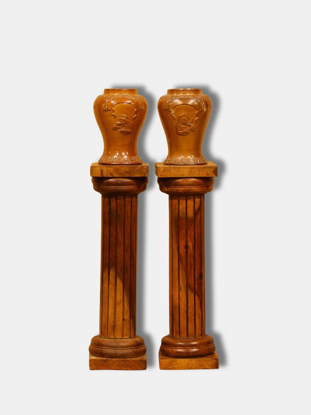 A pair of turned and fluted warm brown hardwood Neoclassical column pedestals with square base plinths and capital tops. View II