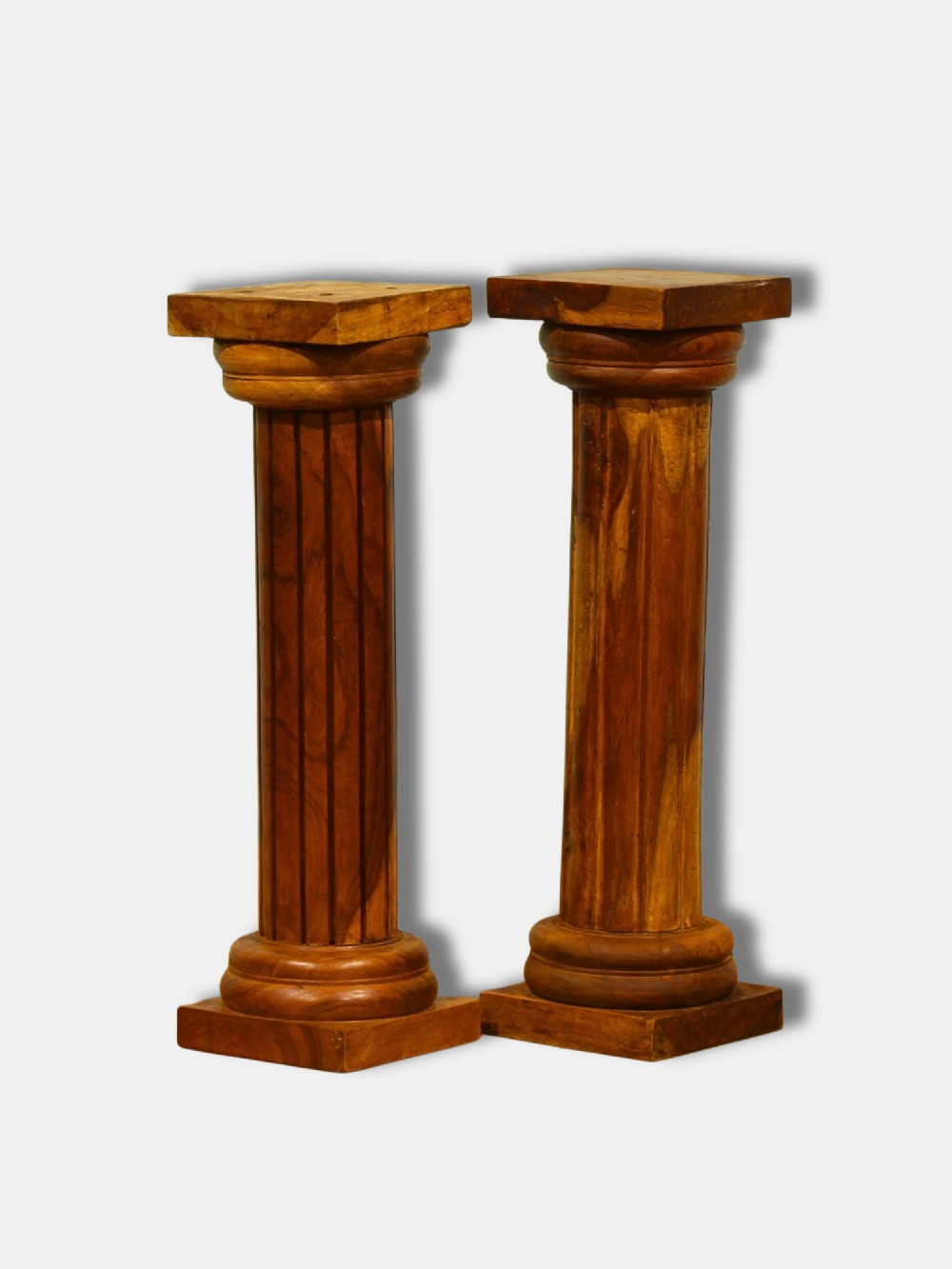 A pair of warm brown turned hardwood column pedestals featuring fluted shafts, square capital tops, and moulded square bases.