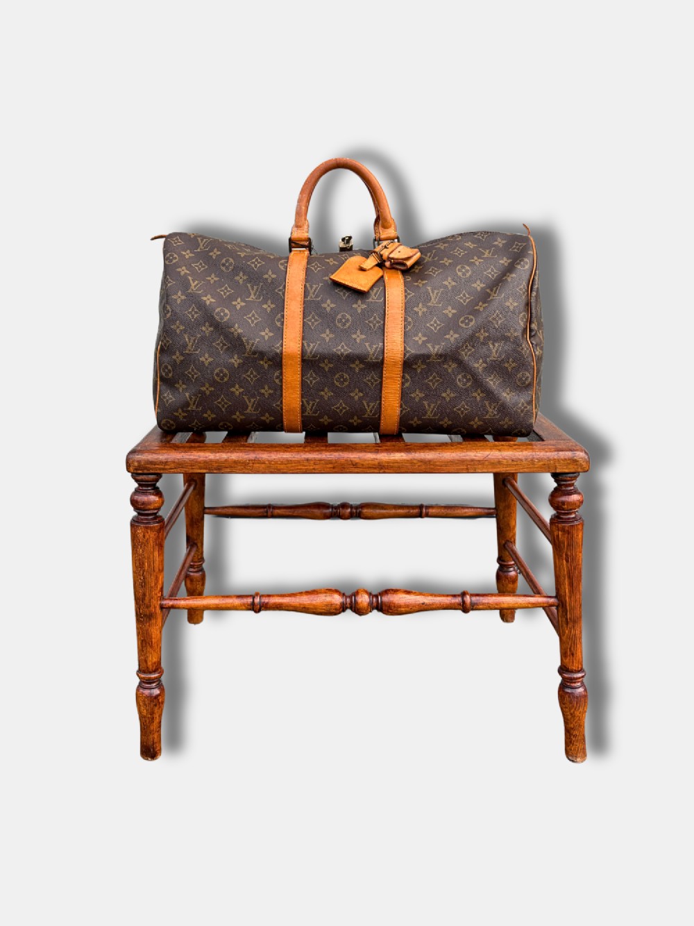 An antique c. 1900 English oak luggage stand featuring a slatted top frame and turned wooden legs with stretchers. View II