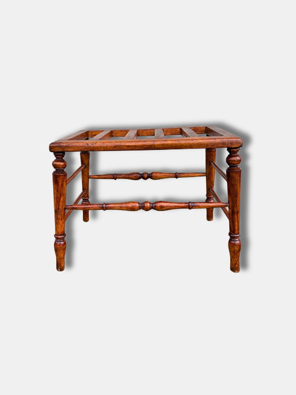 An antique c. 1900 English oak luggage stand featuring a slatted top frame and turned wooden legs with stretchers. View III