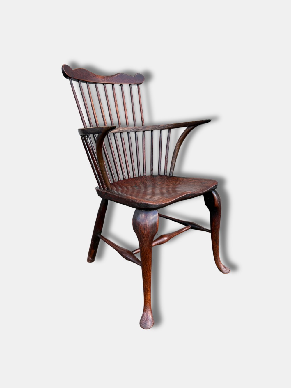 An antique dark yewwood comb back Windsor armchair featuring turned back spindles, shaped armrests, a contoured solid seat, and cabriole front legs. View II