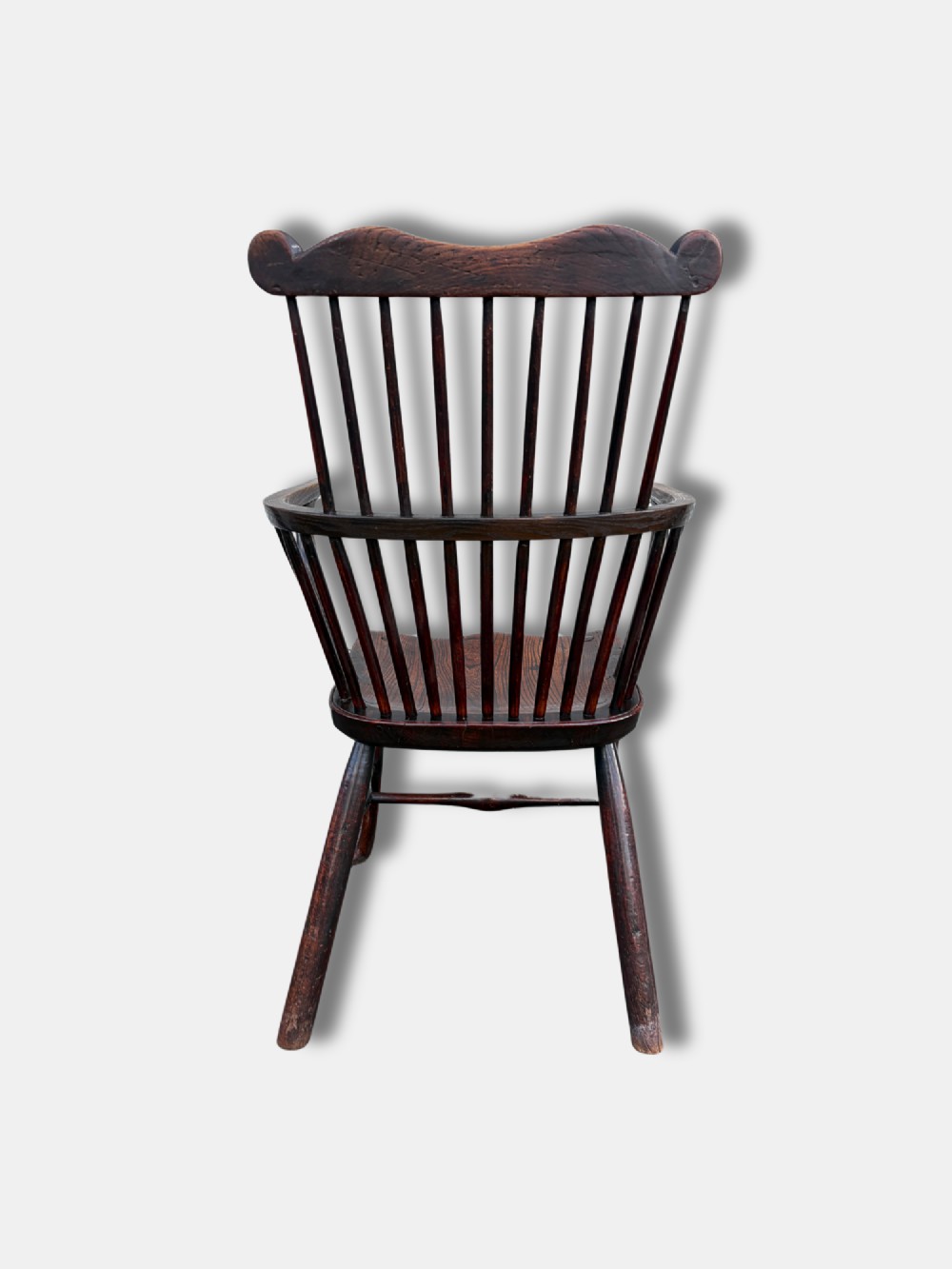 An antique dark yewwood comb back Windsor armchair featuring turned back spindles, shaped armrests, a contoured solid seat, and cabriole front legs. View V
