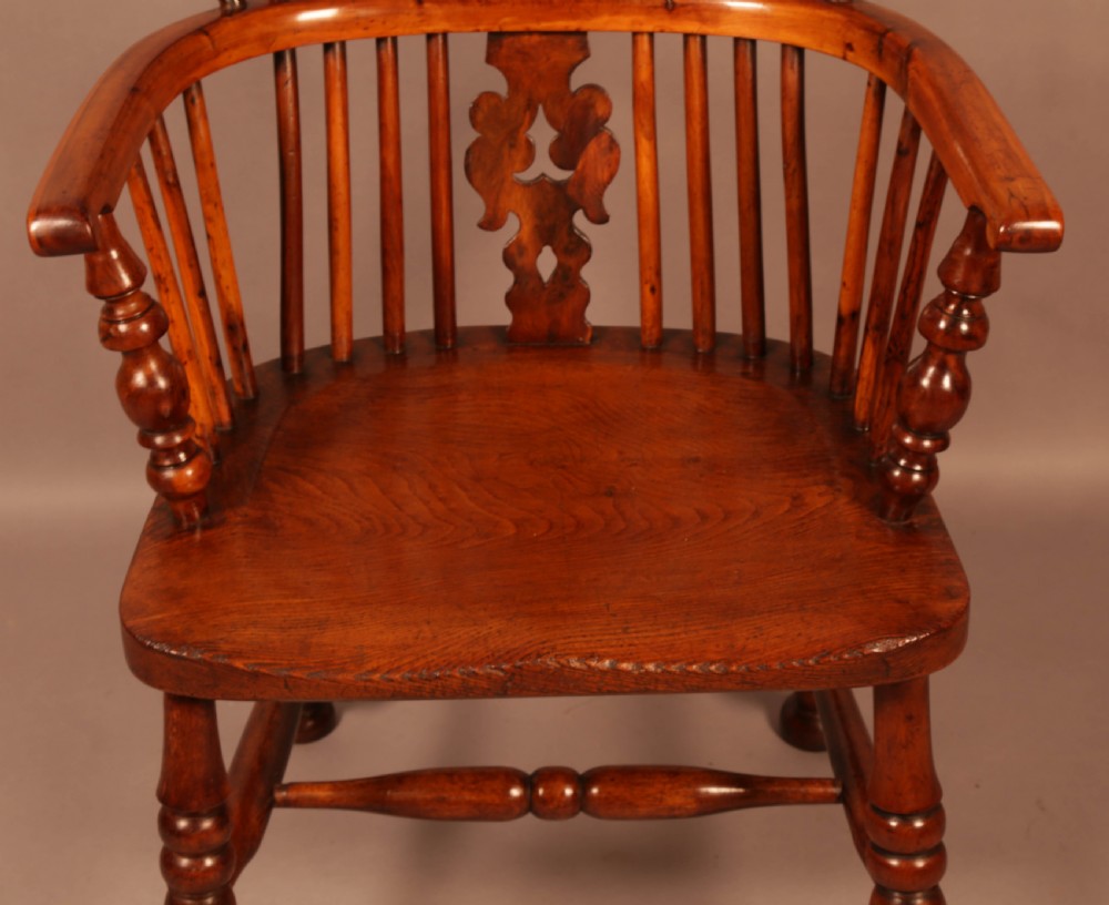 A mid-19th century high-back yew wood Windsor armchair featuring a pierced central splat, steam-bent armrests, shaped seat, and turned legs. View IV