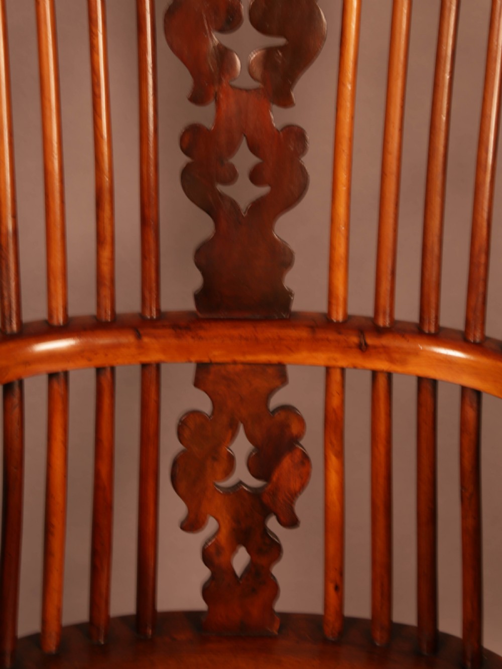 A mid-19th century high-back yew wood Windsor armchair featuring a pierced central splat, steam-bent armrests, shaped seat, and turned legs. View IX