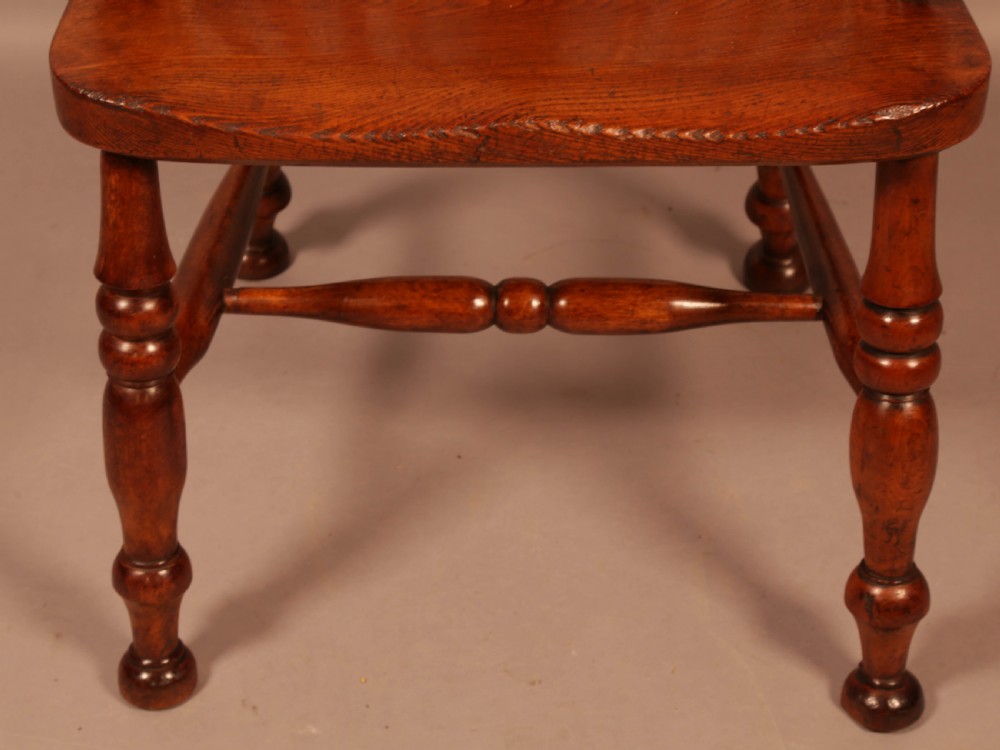 A mid-19th century high-back yew wood Windsor armchair featuring a pierced central splat, steam-bent armrests, shaped seat, and turned legs. View X