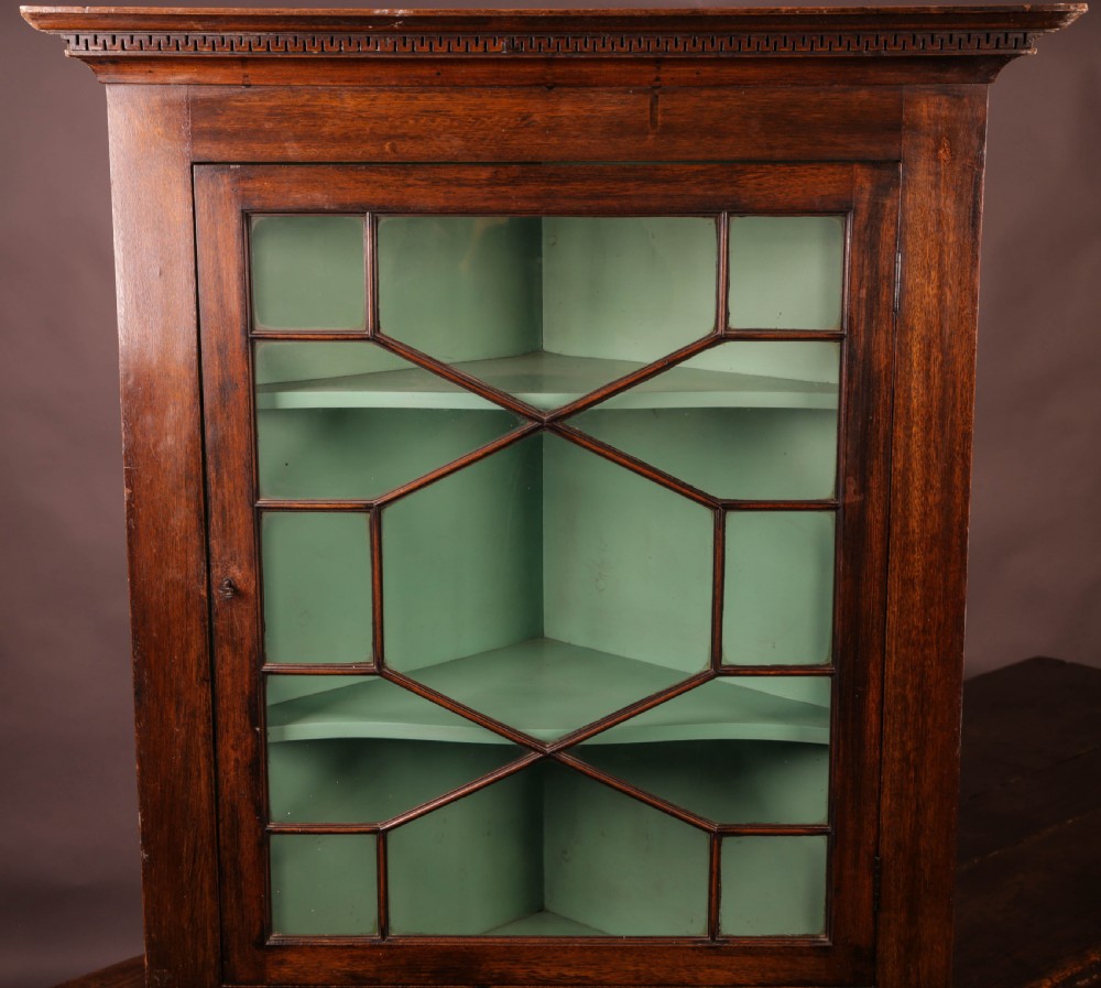 A Georgian mahogany corner cupboard featuring an astragal glazed door, dentil moulding along the cornice, and a painted green interior with three shelves. View II