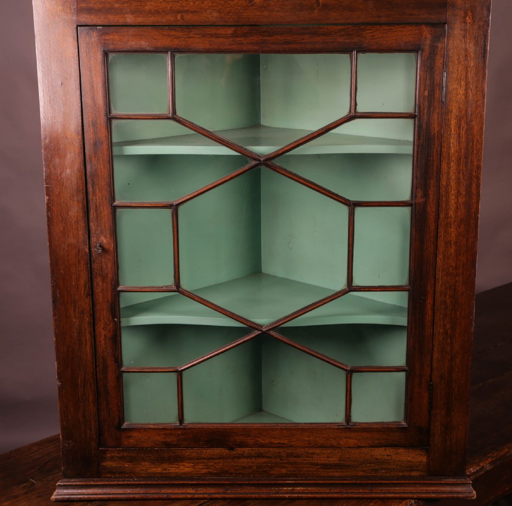 A Georgian mahogany corner cupboard featuring an astragal glazed door, dentil moulding along the cornice, and a painted green interior with three shelves. View III