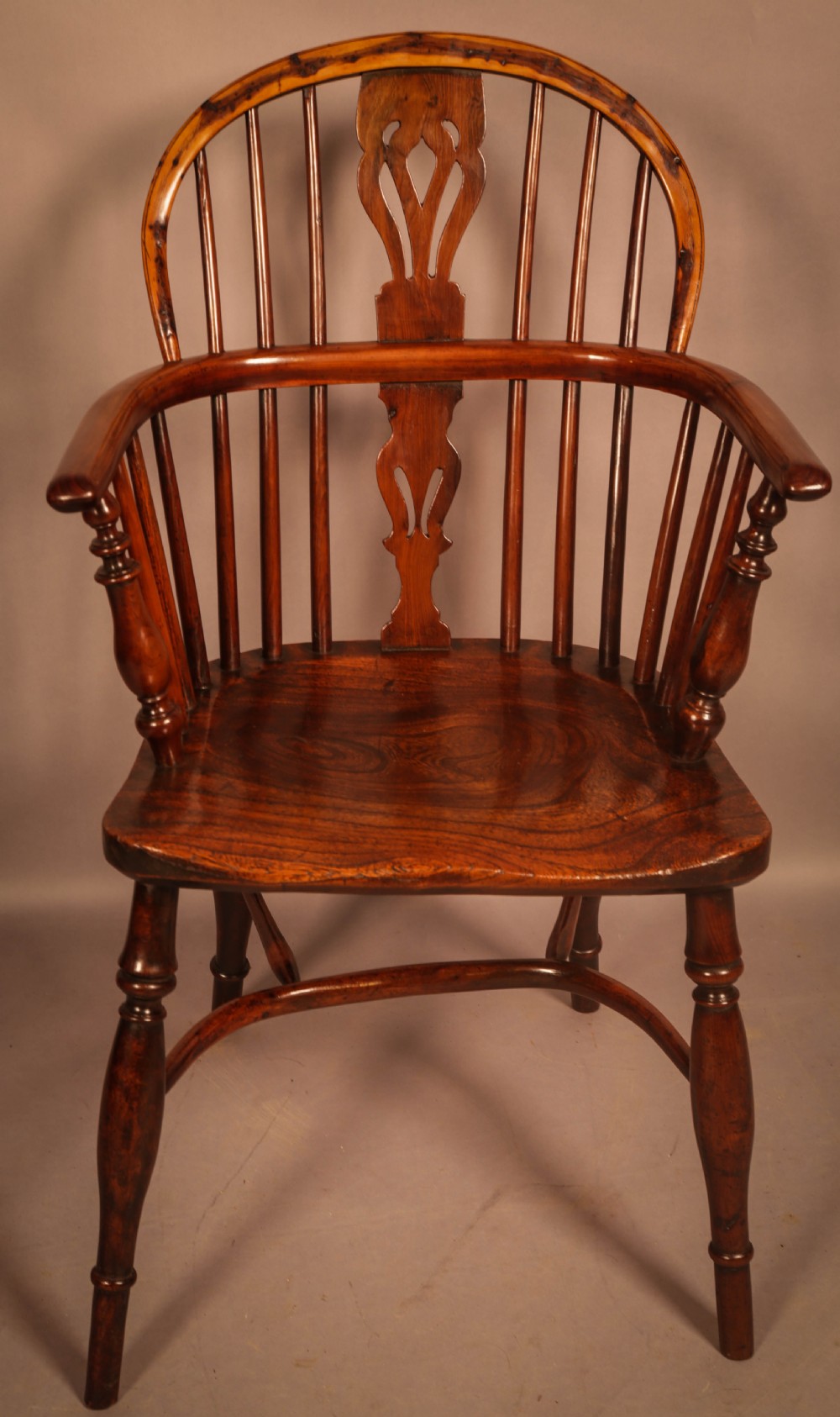A traditional yew wood low-back Windsor armchair featuring a curved bow armrest, spindle back with central pierced splat, shaped solid seat, and turned legs with a crinoline stretcher. View II