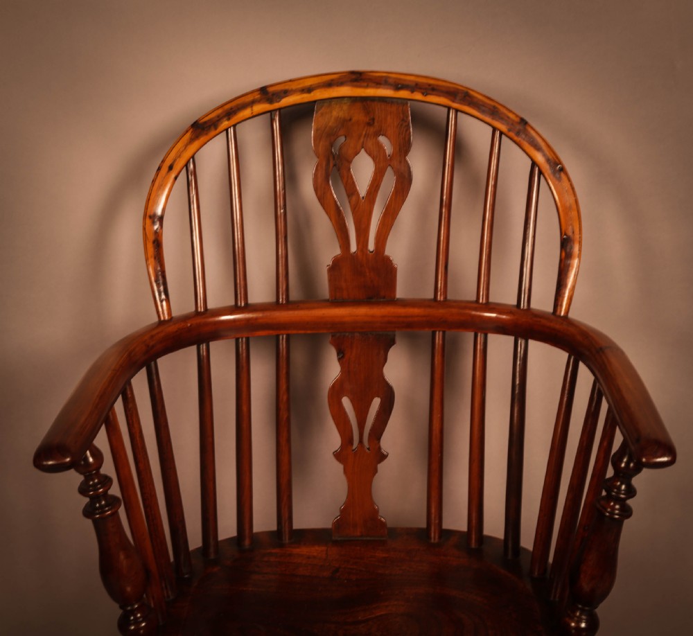 A traditional yew wood low-back Windsor armchair featuring a curved bow armrest, spindle back with central pierced splat, shaped solid seat, and turned legs with a crinoline stretcher. View IV