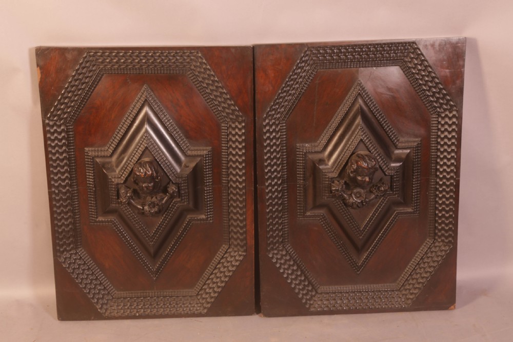 A pair of rectangular dark oak door panels featuring central raised diamond motifs carved with human heads and intricate geometric chip-carving borders. View II