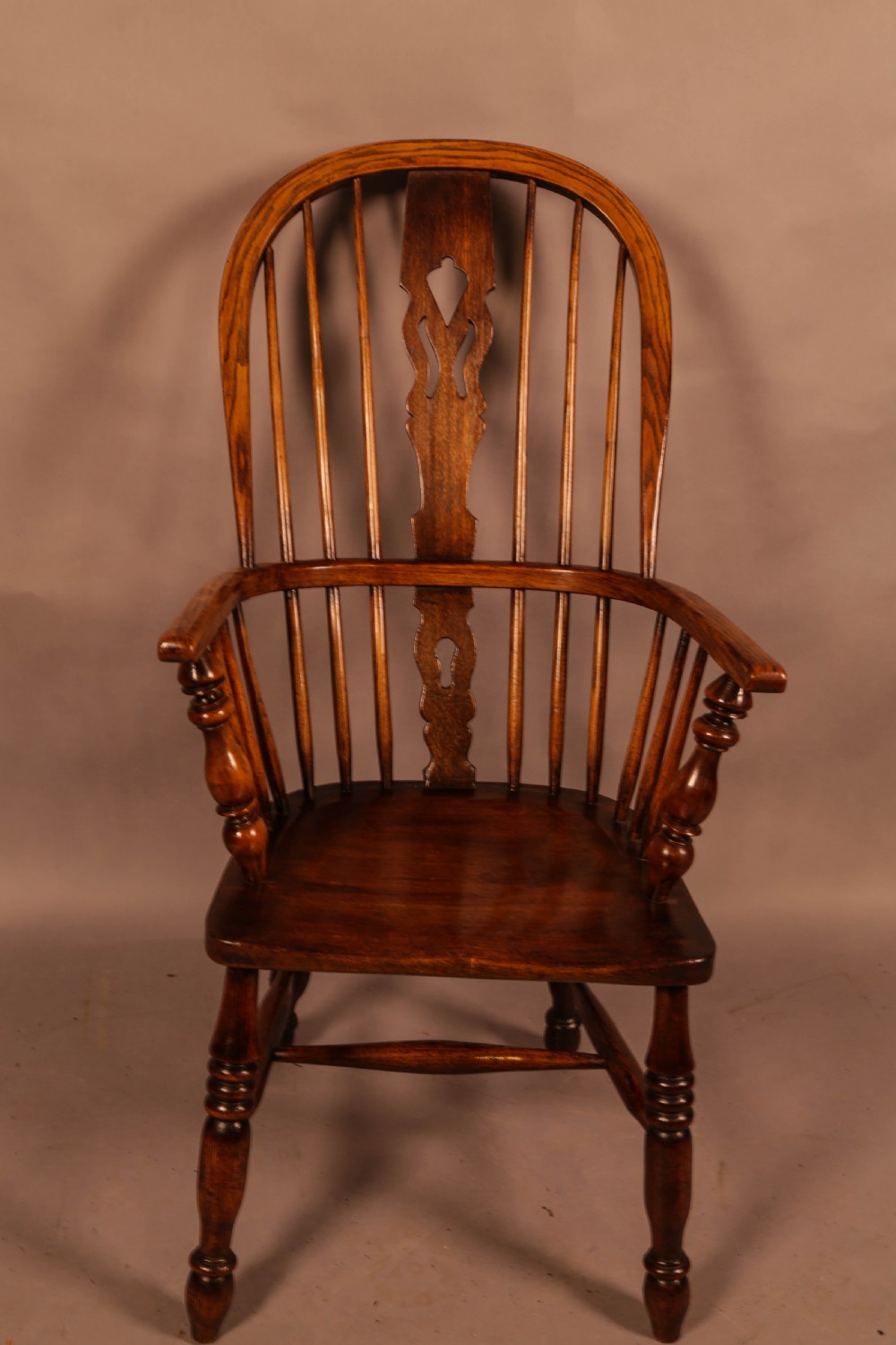 An antique high-back Windsor armchair crafted from ash and elm timber with turned legs and a pierced back splat. View II