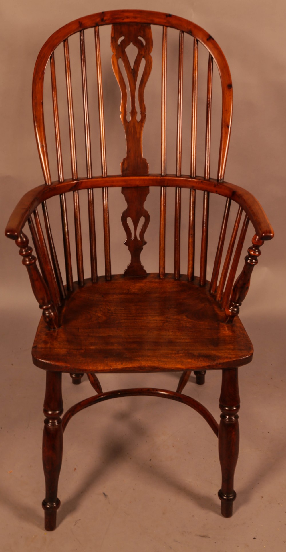 A high-backed wooden Windsor armchair featuring a pierced splat, slender spindles, and turned legs joined by an H-stretcher. View II