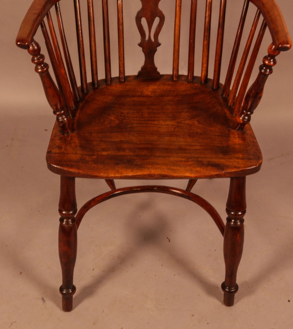 A high-backed wooden Windsor armchair featuring a pierced splat, slender spindles, and turned legs joined by an H-stretcher. View III