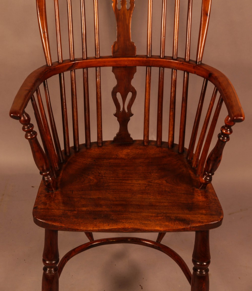 A high-backed wooden Windsor armchair featuring a pierced splat, slender spindles, and turned legs joined by an H-stretcher. View IV