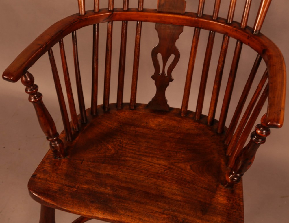 A high-backed wooden Windsor armchair featuring a pierced splat, slender spindles, and turned legs joined by an H-stretcher. View VI