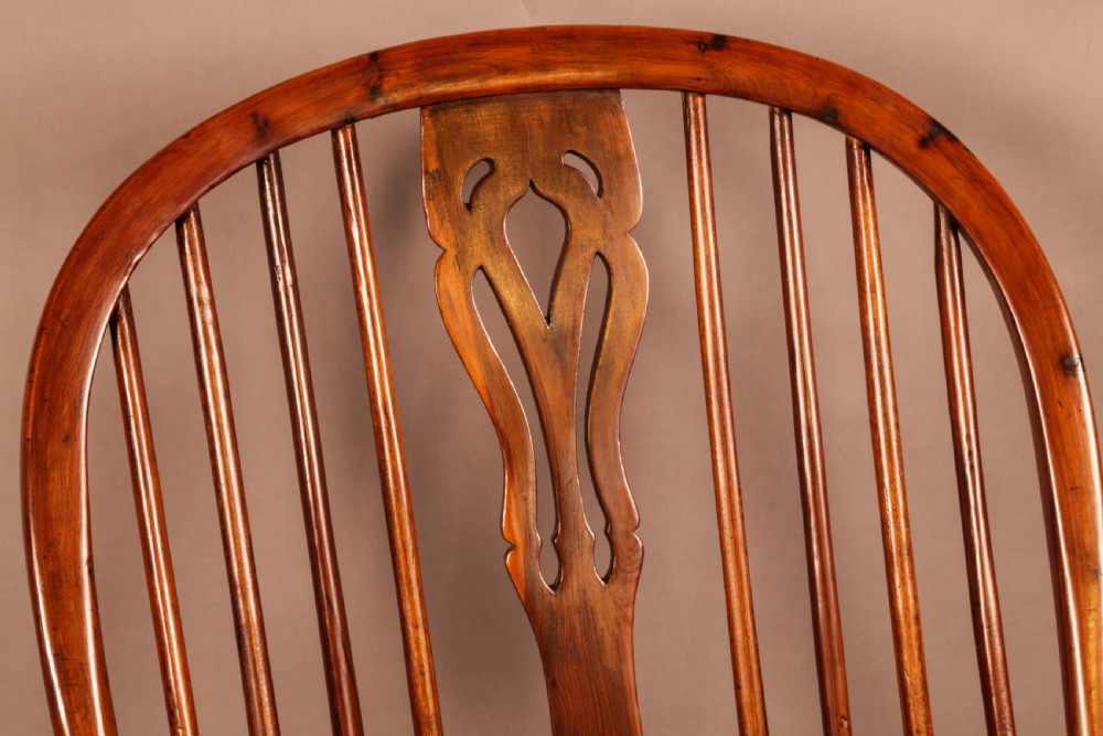 A high-backed wooden Windsor armchair featuring a pierced splat, slender spindles, and turned legs joined by an H-stretcher. View IX