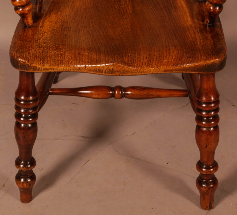 An antique brown yew wood Windsor armchair featuring a hoop back, a central pierced splat, turned spindles, broad armrests, and turned legs. View IV