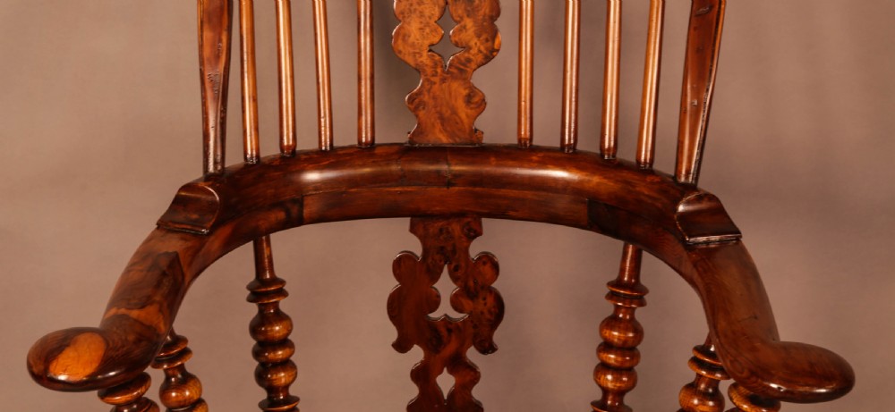 An antique brown yew wood Windsor armchair featuring a hoop back, a central pierced splat, turned spindles, broad armrests, and turned legs. View VI