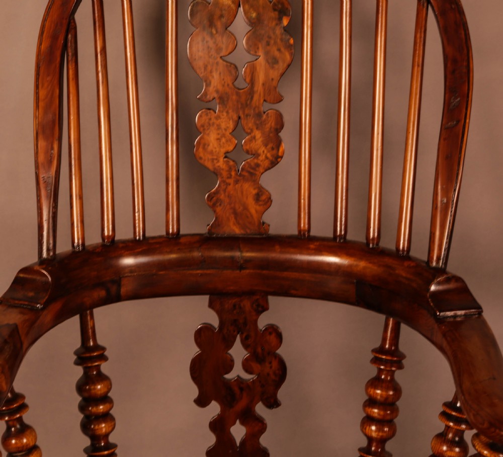 An antique brown yew wood Windsor armchair featuring a hoop back, a central pierced splat, turned spindles, broad armrests, and turned legs. View VII