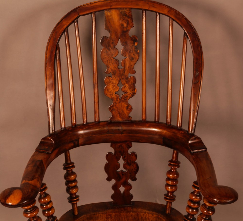 An antique brown yew wood Windsor armchair featuring a hoop back, a central pierced splat, turned spindles, broad armrests, and turned legs. View VIII