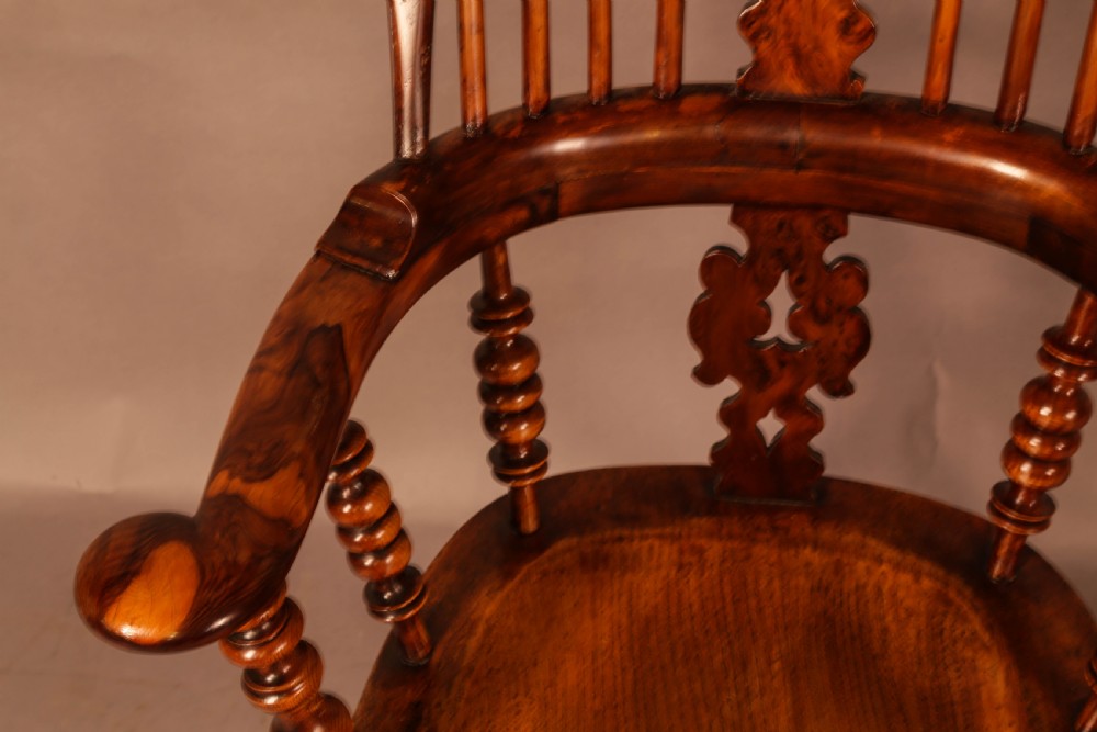 An antique brown yew wood Windsor armchair featuring a hoop back, a central pierced splat, turned spindles, broad armrests, and turned legs. View IX