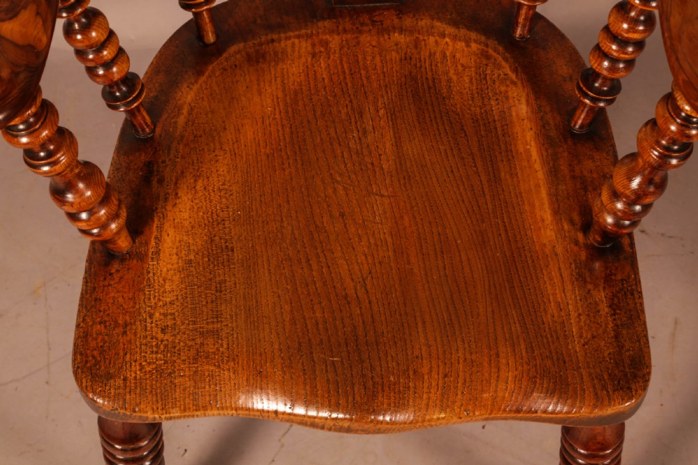An antique brown yew wood Windsor armchair featuring a hoop back, a central pierced splat, turned spindles, broad armrests, and turned legs. View XI