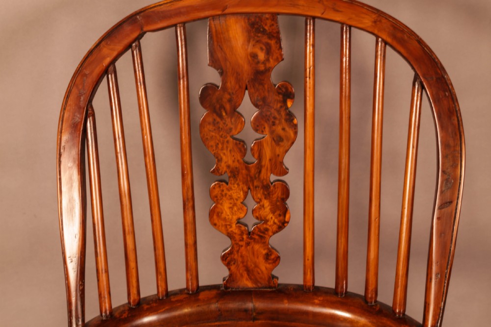 An antique brown yew wood Windsor armchair featuring a hoop back, a central pierced splat, turned spindles, broad armrests, and turned legs. View XII