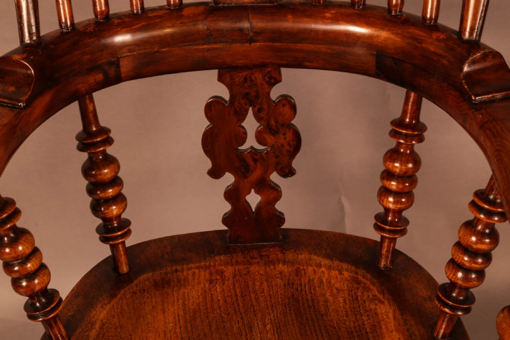 An antique brown yew wood Windsor armchair featuring a hoop back, a central pierced splat, turned spindles, broad armrests, and turned legs. View XIII