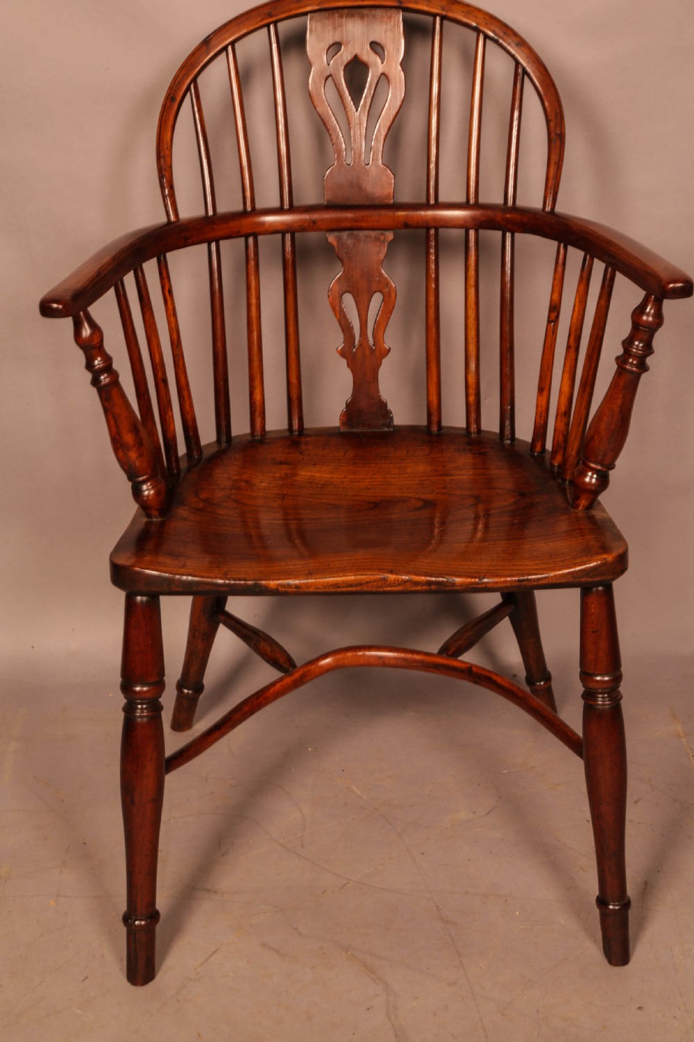 A yew wood low-back Windsor armchair featuring a curved top rail, pierced back splat, spindled arms, shaped solid seat, turned legs, and a crinoline stretcher. View II