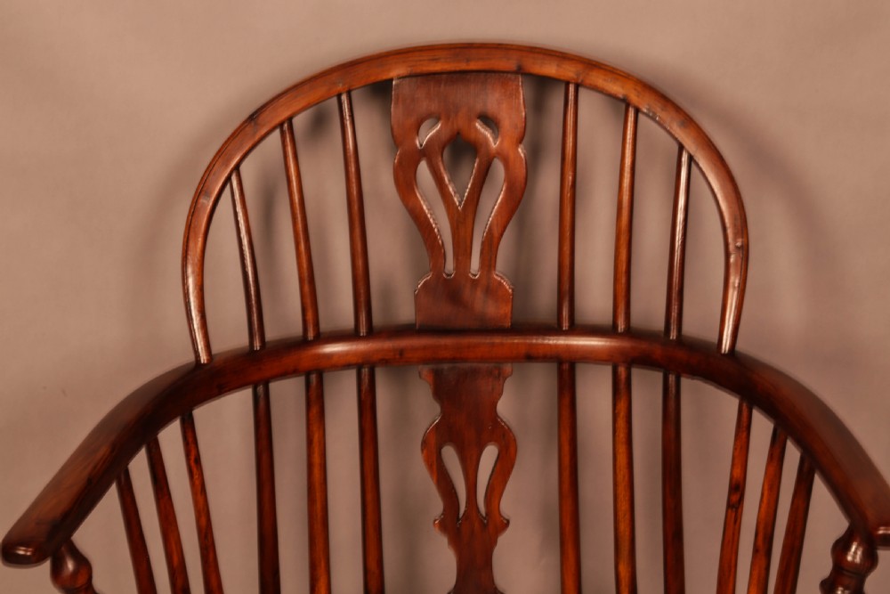 A yew wood low-back Windsor armchair featuring a curved top rail, pierced back splat, spindled arms, shaped solid seat, turned legs, and a crinoline stretcher. View V