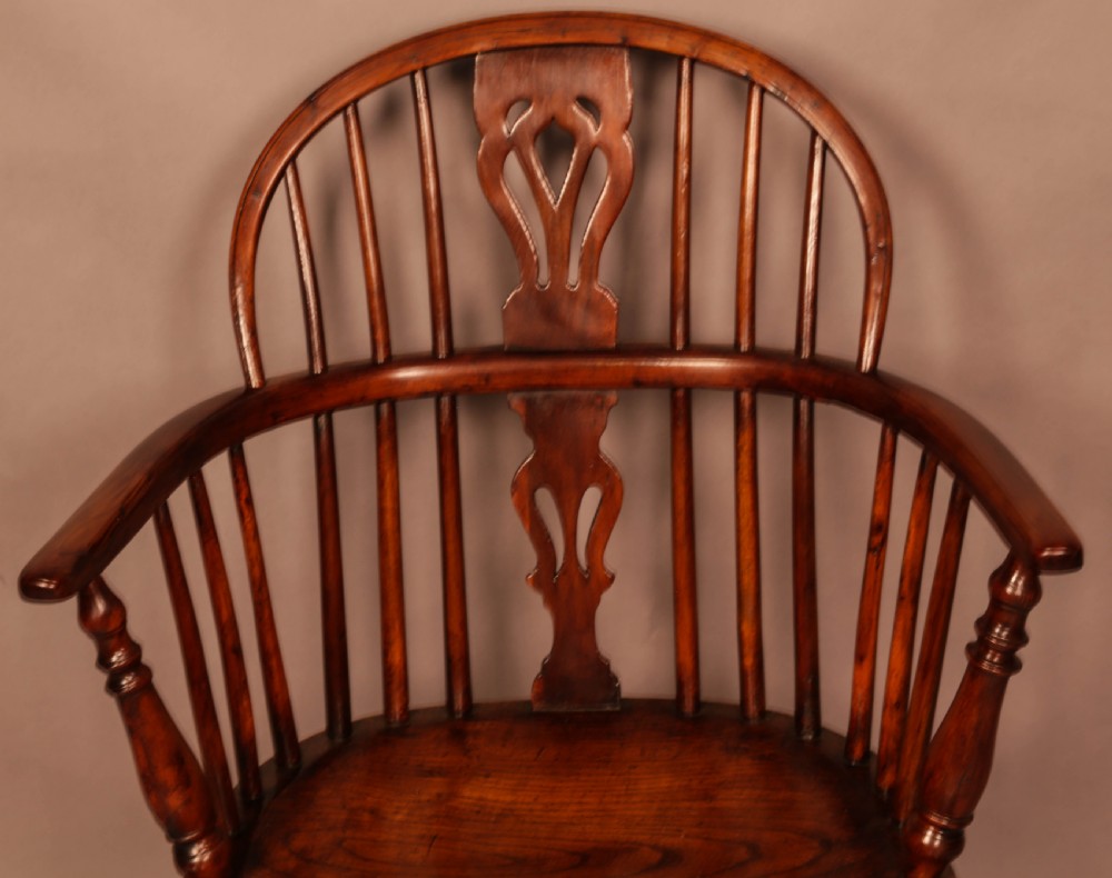 A yew wood low-back Windsor armchair featuring a curved top rail, pierced back splat, spindled arms, shaped solid seat, turned legs, and a crinoline stretcher. View VI