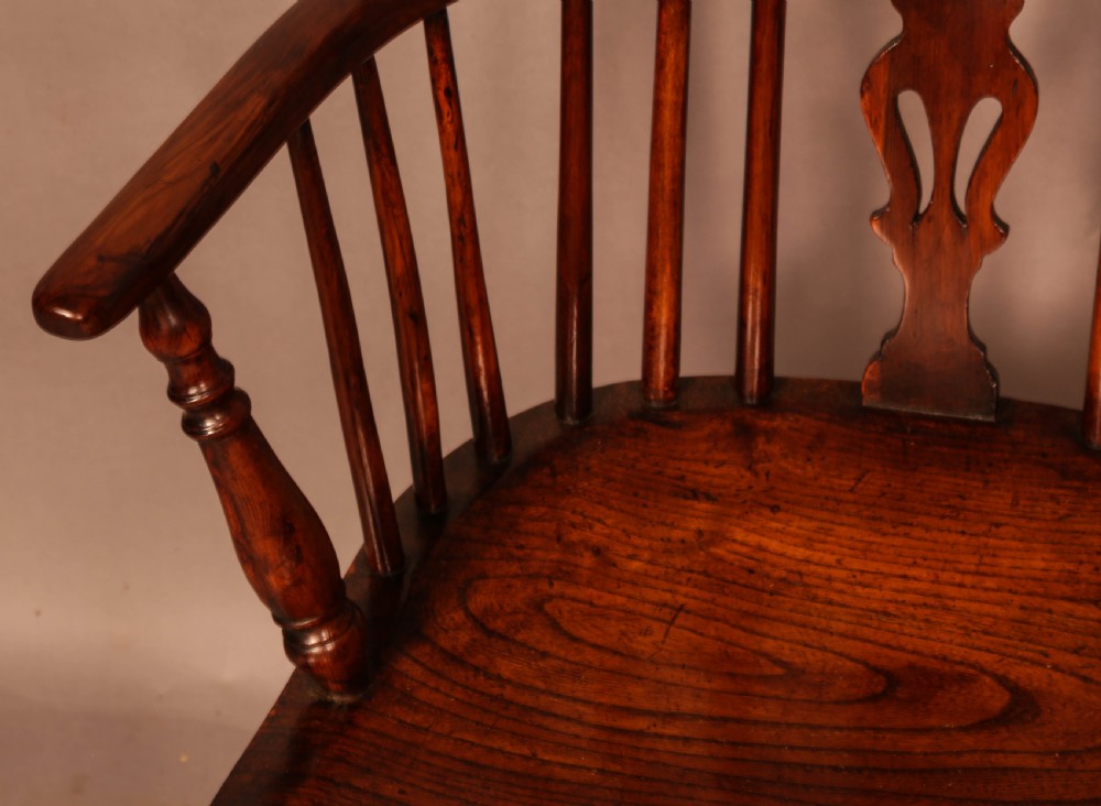 A yew wood low-back Windsor armchair featuring a curved top rail, pierced back splat, spindled arms, shaped solid seat, turned legs, and a crinoline stretcher. View VII