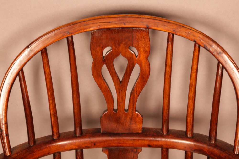 A yew wood low-back Windsor armchair featuring a curved top rail, pierced back splat, spindled arms, shaped solid seat, turned legs, and a crinoline stretcher. View IX