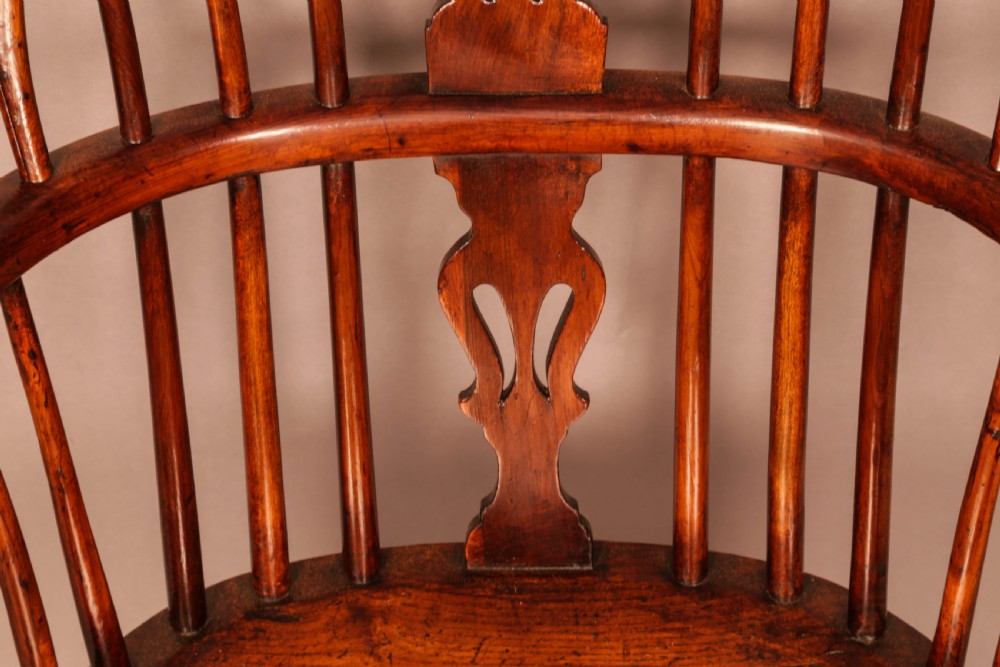A yew wood low-back Windsor armchair featuring a curved top rail, pierced back splat, spindled arms, shaped solid seat, turned legs, and a crinoline stretcher. View X