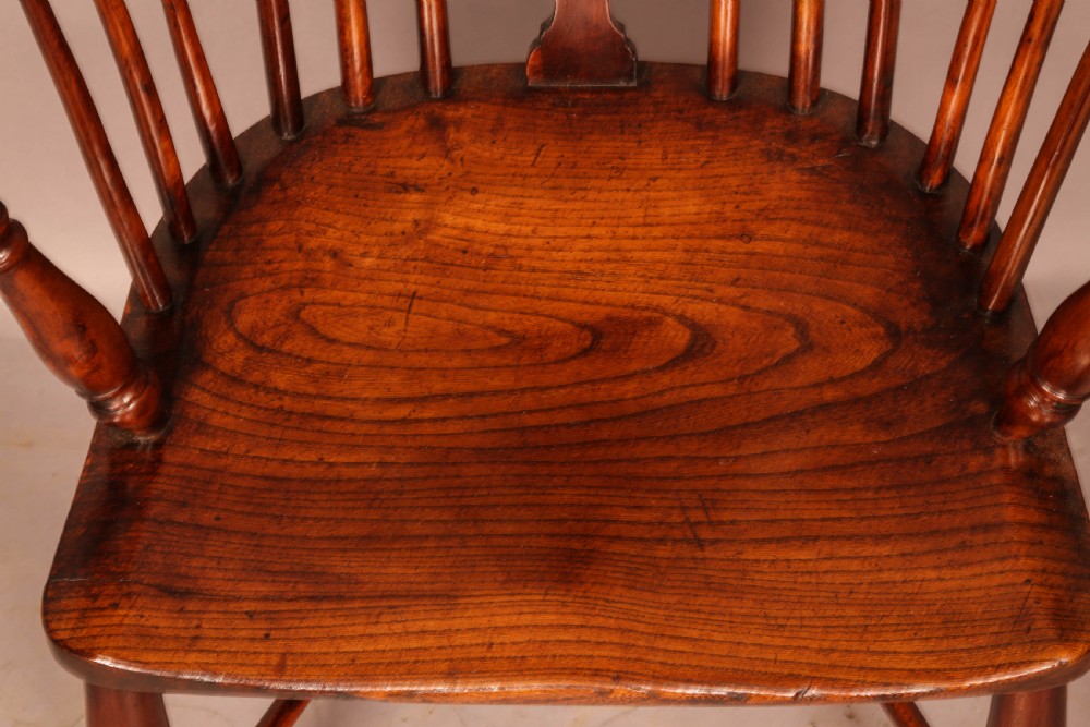 A yew wood low-back Windsor armchair featuring a curved top rail, pierced back splat, spindled arms, shaped solid seat, turned legs, and a crinoline stretcher. View XI