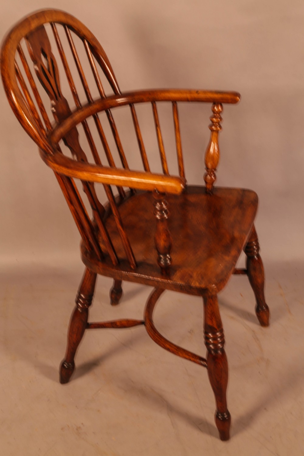 A traditional ash and elm low-back Windsor armchair with a shaped saddle seat, turned legs, and a steam-bent back hoop.