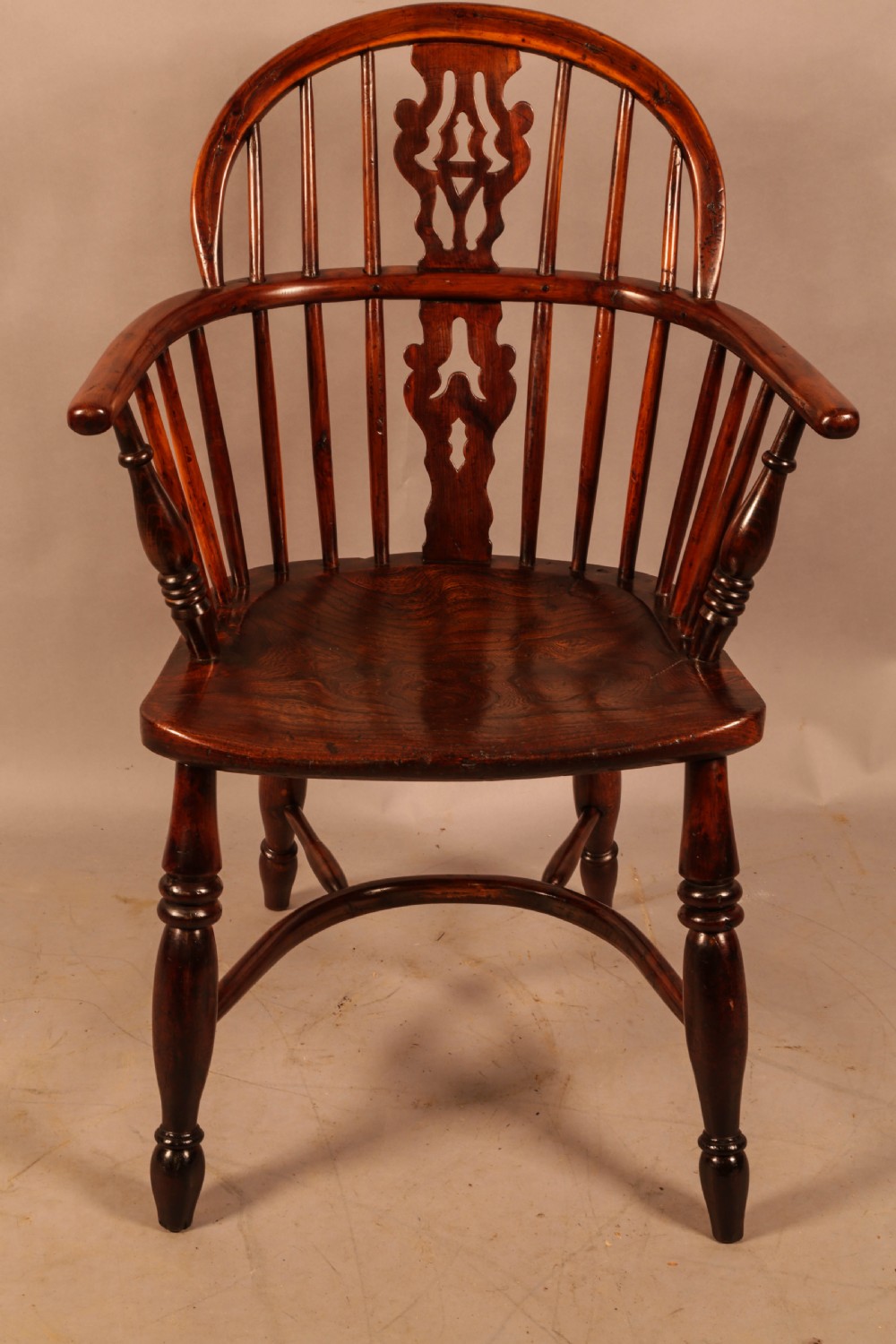 A nineteenth-century yew wood Windsor armchair featuring a curved hoop back, pierced central splat, turned arm supports, shaped saddle seat, and turned legs with a crinoline stretcher. View II