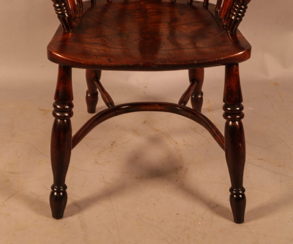 A nineteenth-century yew wood Windsor armchair featuring a curved hoop back, pierced central splat, turned arm supports, shaped saddle seat, and turned legs with a crinoline stretcher. View III