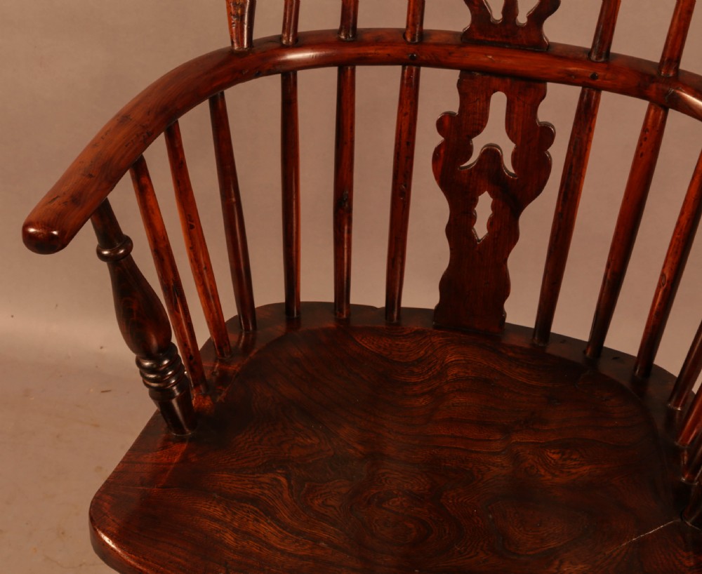 A nineteenth-century yew wood Windsor armchair featuring a curved hoop back, pierced central splat, turned arm supports, shaped saddle seat, and turned legs with a crinoline stretcher. View IV