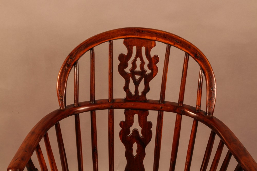 A nineteenth-century yew wood Windsor armchair featuring a curved hoop back, pierced central splat, turned arm supports, shaped saddle seat, and turned legs with a crinoline stretcher. View VI