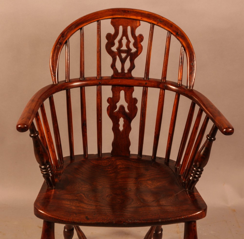 A nineteenth-century yew wood Windsor armchair featuring a curved hoop back, pierced central splat, turned arm supports, shaped saddle seat, and turned legs with a crinoline stretcher. View VII