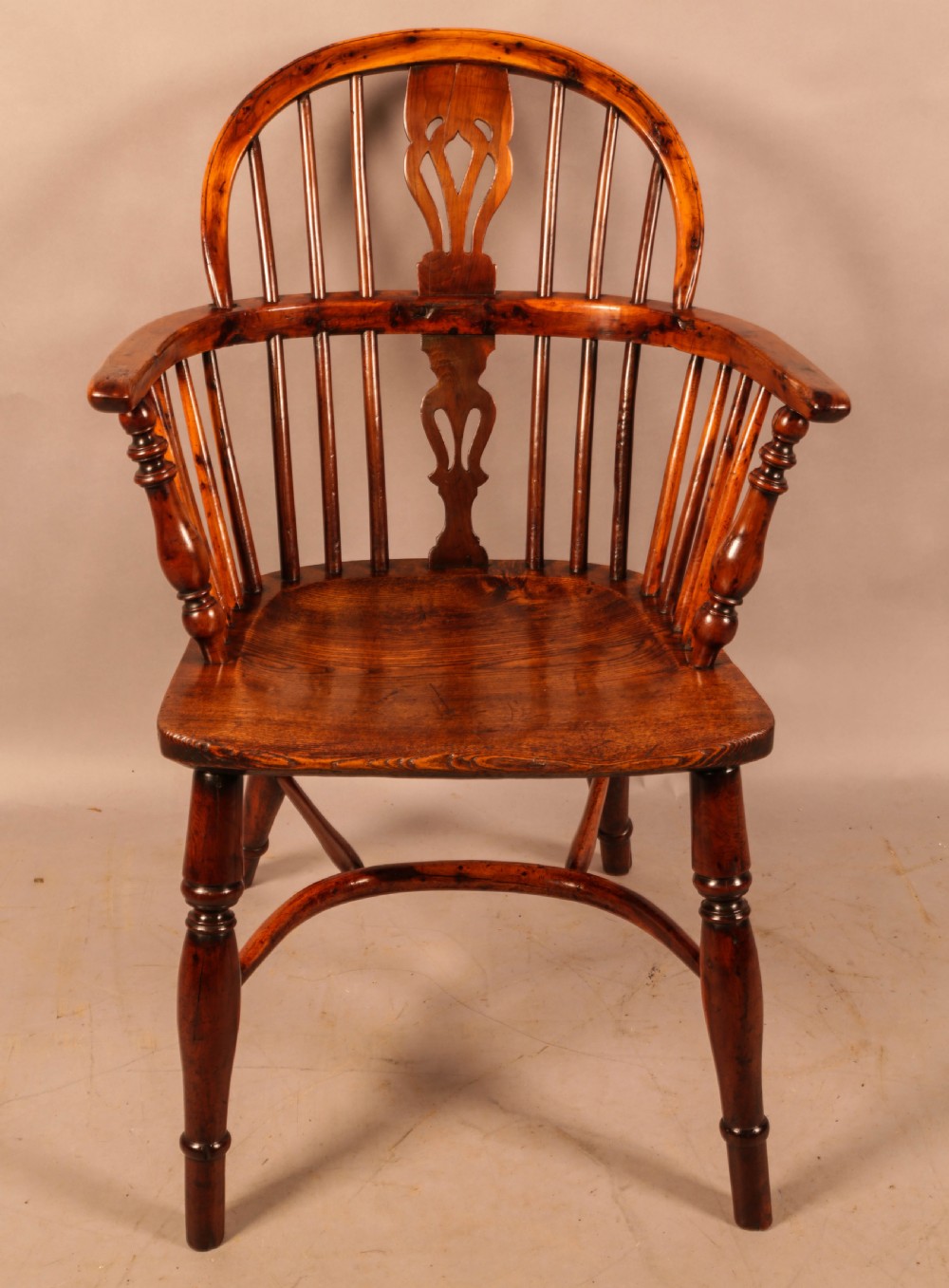 An antique yew wood low-back Windsor armchair featuring turned legs, a crinoline stretcher, and a pierced splat. View II