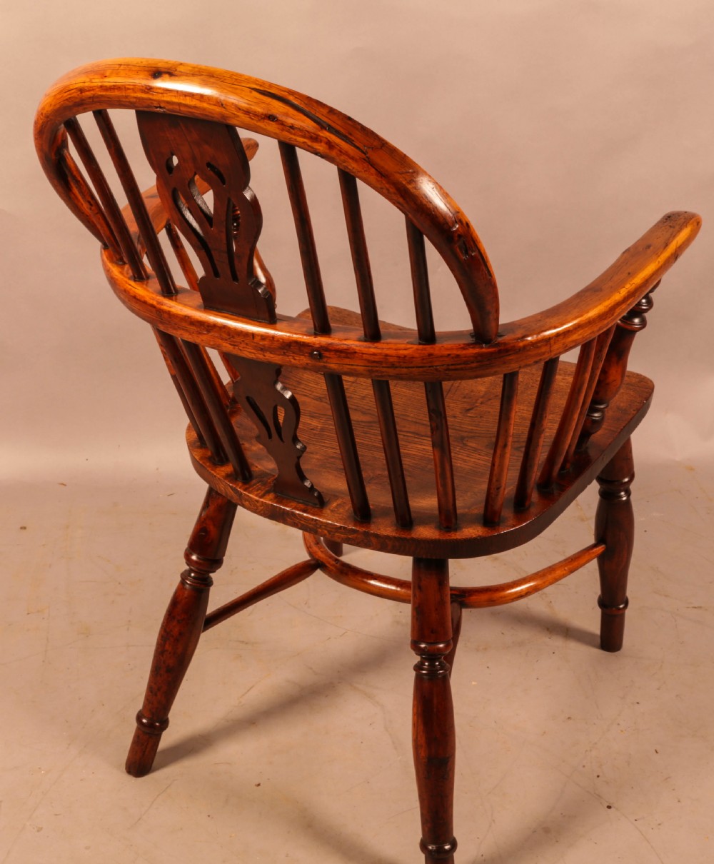An antique yew wood low-back Windsor armchair featuring turned legs, a crinoline stretcher, and a pierced splat. View III