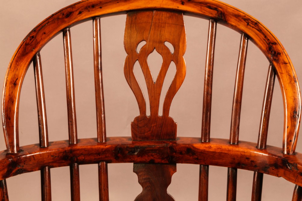 An antique yew wood low-back Windsor armchair featuring turned legs, a crinoline stretcher, and a pierced splat. View IV