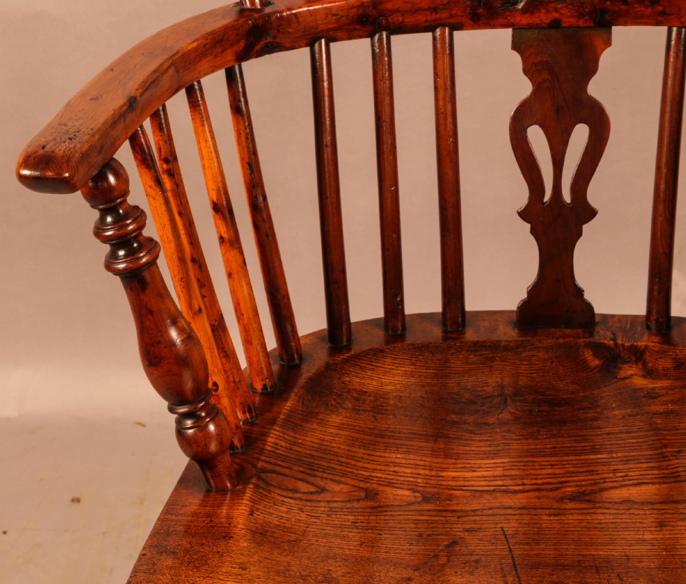 An antique yew wood low-back Windsor armchair featuring turned legs, a crinoline stretcher, and a pierced splat. View X