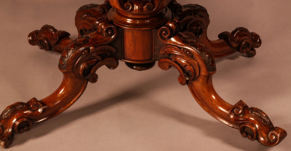 A Victorian burr walnut breakfast table featuring a shaped serpentine top resting on a central carved pedestal column with four scroll-carved legs. View II